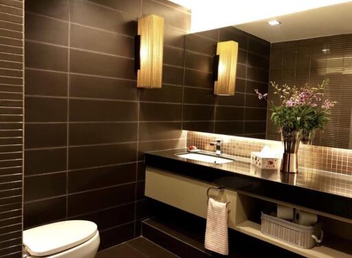 Modern bathroom with dark tiles, floating sink, and decorative lighting