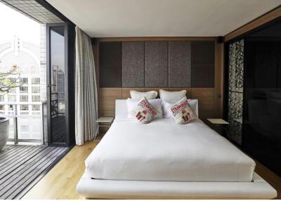 Modern bedroom with a balcony view, featuring a neatly made bed and stylish decor.