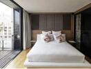 Modern bedroom with a balcony view, featuring a neatly made bed and stylish decor.