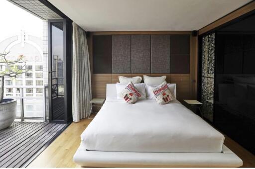 Modern bedroom with a balcony view, featuring a neatly made bed and stylish decor.