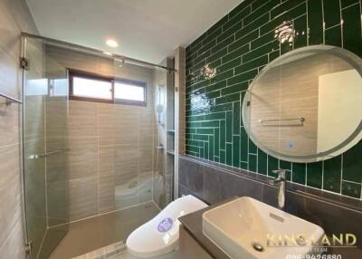 Modern bathroom with glass shower, green tiled wall, and sink