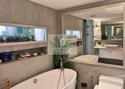 Modern bathroom with a large mirror, bathtub, and decorated shelves