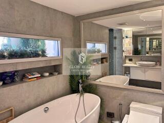 Modern bathroom with a large mirror, bathtub, and decorated shelves