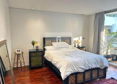 Spacious bedroom with a double bed, bedside tables, and a large window