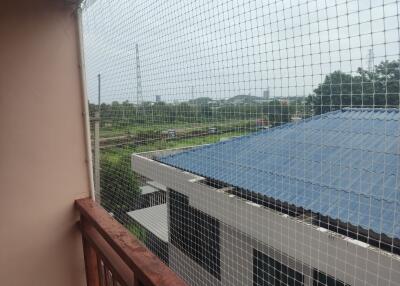 Balcony view with safety net and overlooking nearby buildings and greenery.