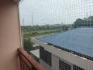 Balcony view with safety net and overlooking nearby buildings and greenery.