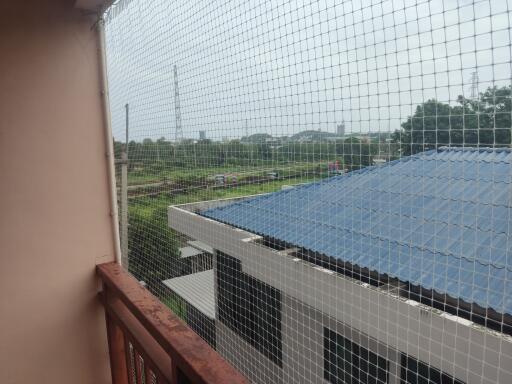 Balcony view with safety net and overlooking nearby buildings and greenery.