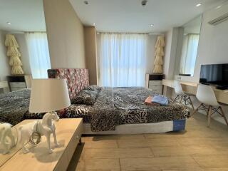 Modern bedroom with a large bed, work desk, and natural light.