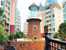 Exterior view of residential buildings with a unique tower structure, balconies, and landscaping