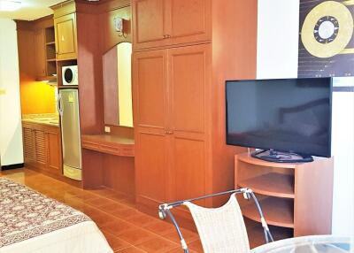 Bedroom with built-in wooden wardrobe, TV, and kitchenette