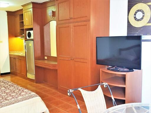 Bedroom with built-in wooden wardrobe, TV, and kitchenette