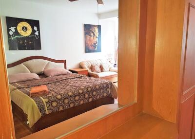 Bedroom with an ornate bedspread, paintings, and a ceiling fan