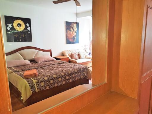 Bedroom with an ornate bedspread, paintings, and a ceiling fan