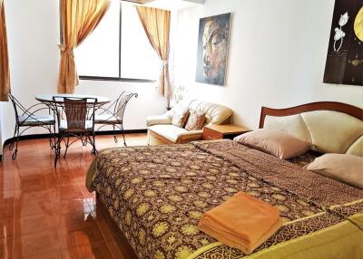 Well-lit bedroom with bed, seating area, and dining table