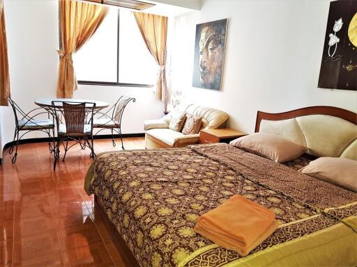 Well-lit bedroom with bed, seating area, and dining table