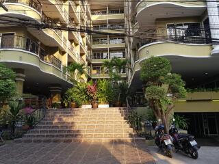 Front view of an apartment building with stairs leading to the entrance