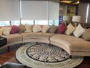 Spacious living room with curved sectional sofa and decorative rug