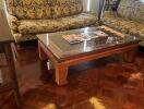 Living room with two patterned sofas, a glass-top wooden coffee table, and glossy parquet flooring