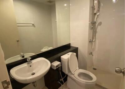 Modern bathroom featuring a wall-mounted sink, toilet, and shower area