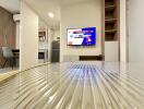 Modern living area with a wall-mounted TV and a view into the kitchen