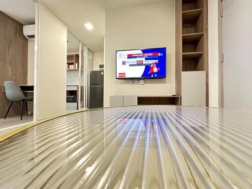 Modern living area with a wall-mounted TV and a view into the kitchen