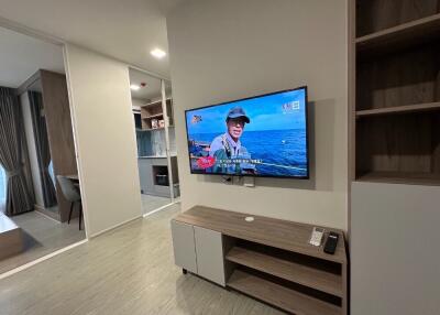 Modern living room with wall-mounted TV and open view to kitchen