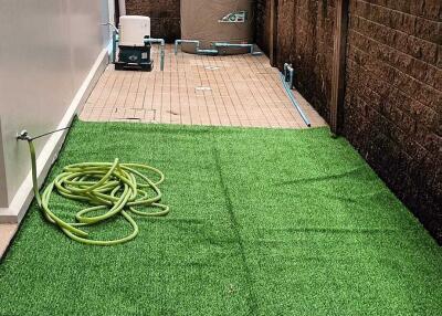 Outdoor space with artificial grass and storage tank