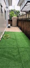 Outdoor space with artificial grass and storage tank