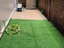 Outdoor space with artificial grass and storage tank