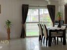 Dining area with table and chairs, window with curtains