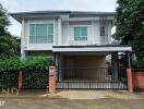 Exterior view of a two-story house with a gated driveway.