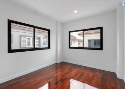 Spacious bedroom with wooden floors and large windows