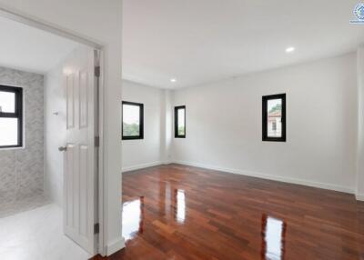 Spacious empty bedroom with wooden flooring and large windows