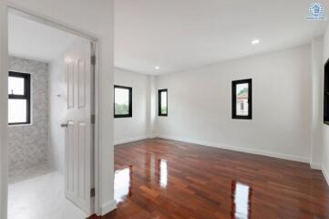 Spacious empty bedroom with wooden flooring and large windows