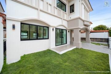 Exterior view of a modern residential building showing lawn and large windows.