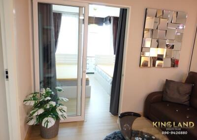 Cozy living room with sofa and decorative mirror, adjacent to a bedroom behind glass sliding doors