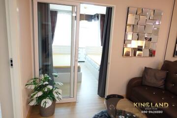 Cozy living room with sofa and decorative mirror, adjacent to a bedroom behind glass sliding doors