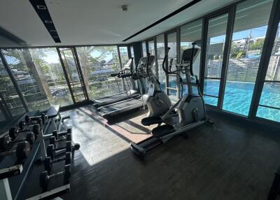 Modern gym with exercise equipment and a view of the pool