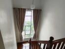 View of an indoor staircase with a window and curtains