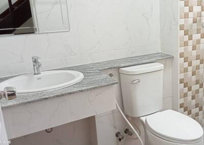 Modern bathroom with sink, toilet, and tiled wall