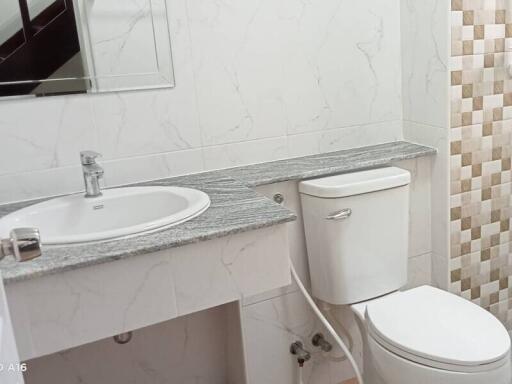 Modern bathroom with sink, toilet, and tiled wall