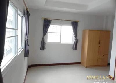 Spacious bedroom with large windows and a wooden wardrobe