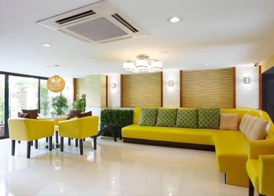 Modern living room with yellow sofas, a dining area, and large windows