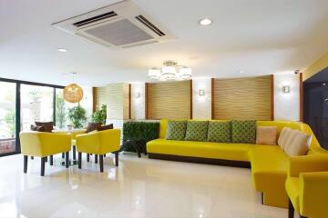 Modern living room with yellow sofas, a dining area, and large windows