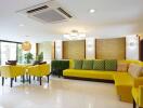 Modern living room with yellow sofas, a dining area, and large windows