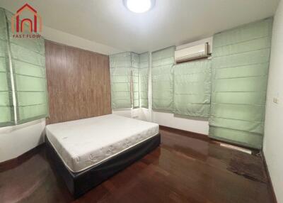 Bedroom with hardwood floors, large windows with green curtains, and a bed