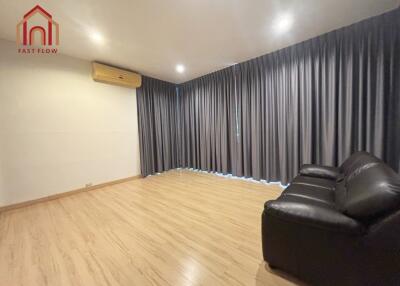 Spacious living room with wooden flooring and large windows covered by grey curtains