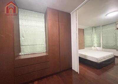 Spacious bedroom with large windows and wooden storage units