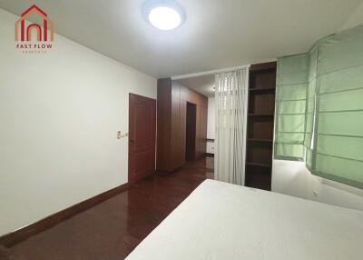 Spacious bedroom with hardwood flooring, green curtains, and ample closet space