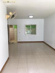 Simple empty living room with tiled floor, fan, window, and access to other rooms